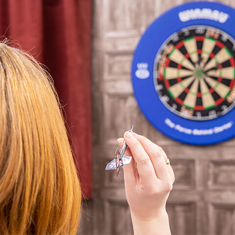 Team member about to throw dart at a dart board