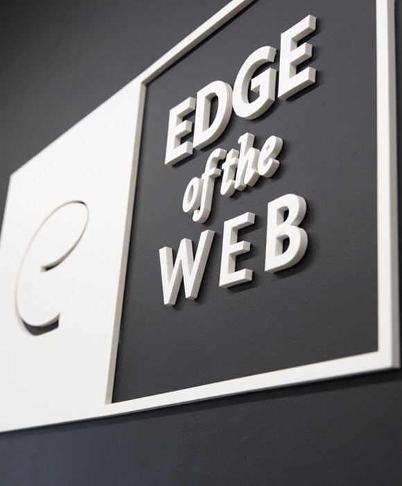 A 3d version of the Edge of the Web logo on a dark wall