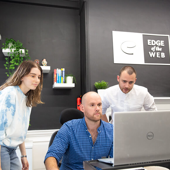 A work team collaborating at a desk on a laptop