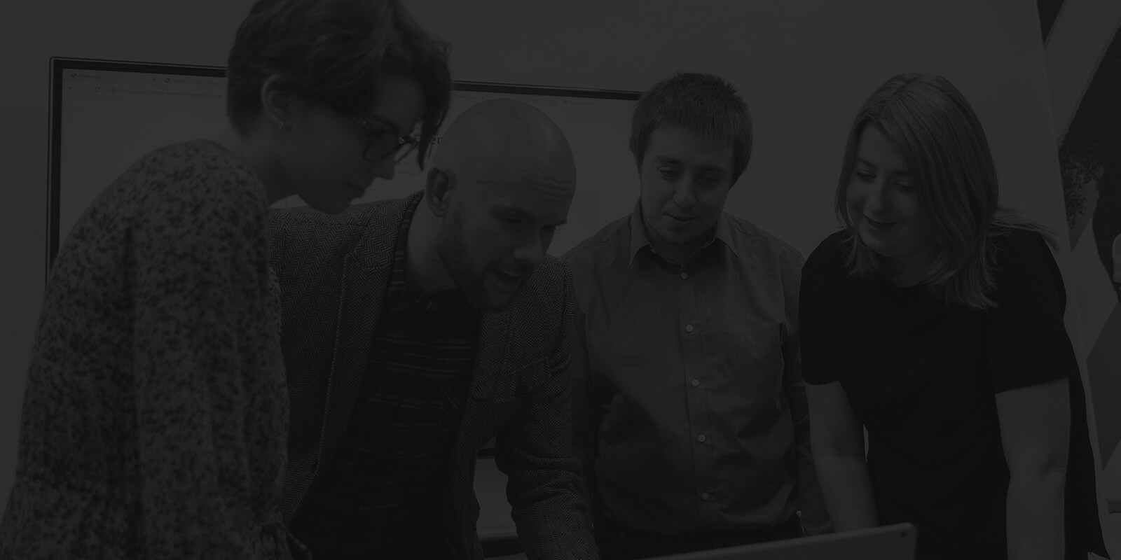 Group of developers and designers gathered around a laptop