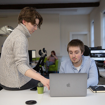 Two developers working together on a Macbook