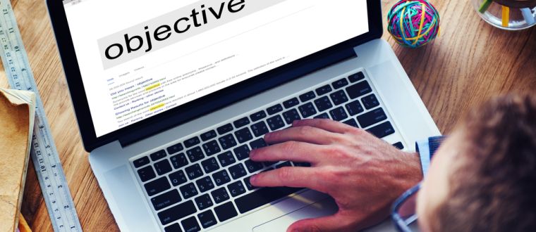 Man typing "objective" into a search engine on his laptop